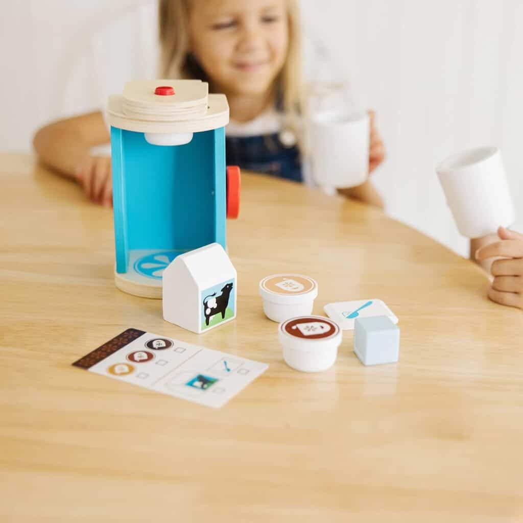 A little girl is playing with a Melissa & Doug Brew and Serve Wooden Coffee Maker Set.