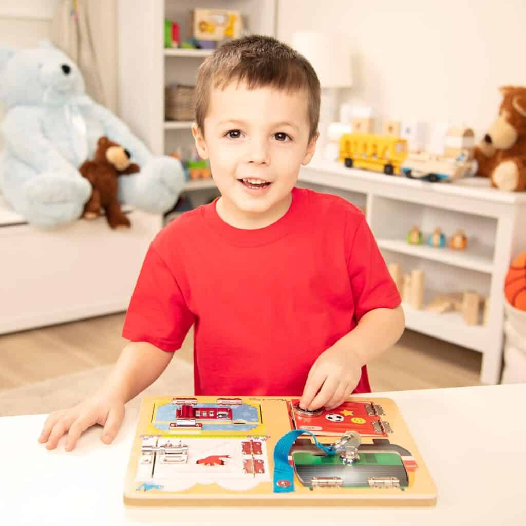 A young boy playing with a Melissa & Doug Locks and Latches Board.