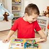 A young boy playing with a Melissa & Doug Locks and Latches Board.