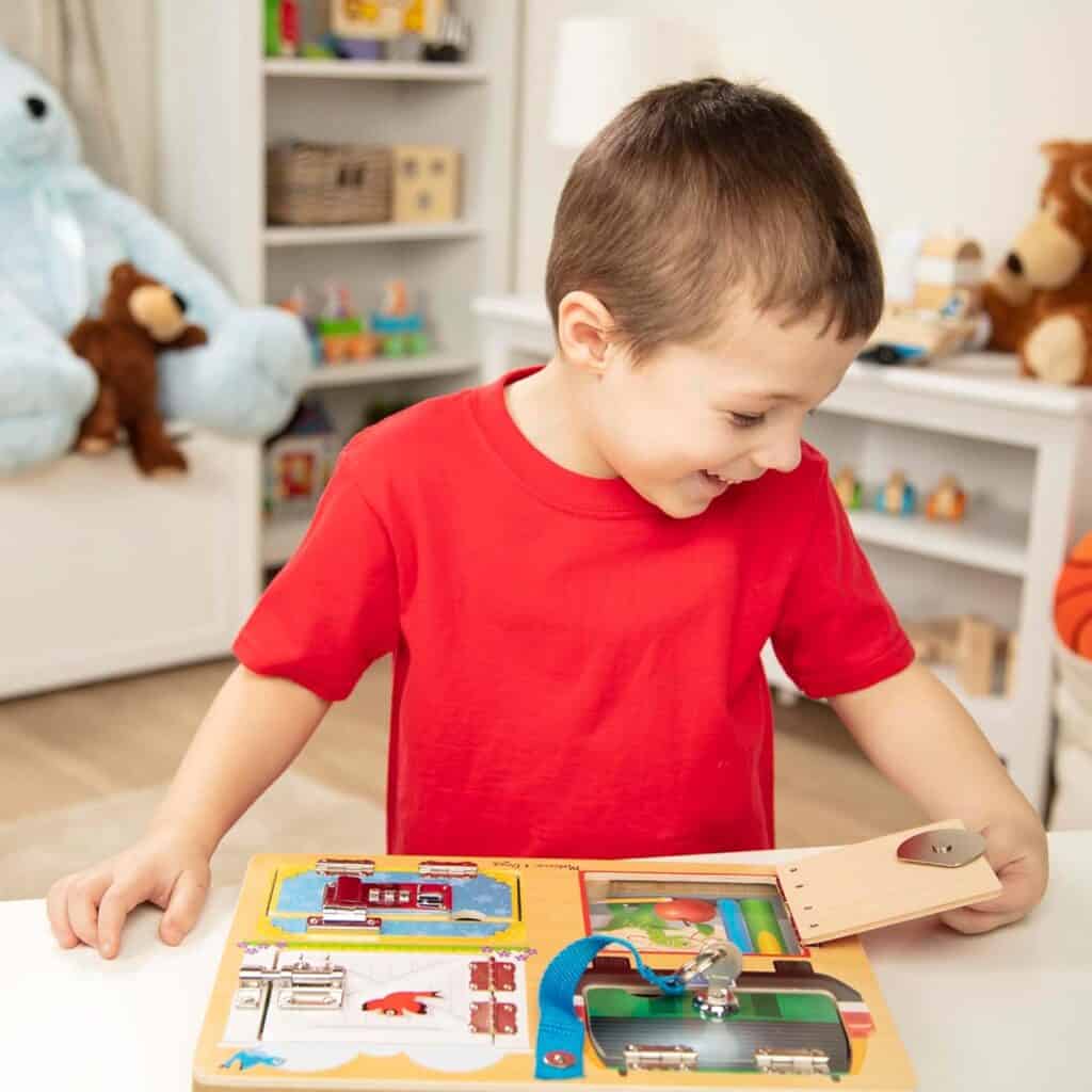A young boy playing with a Melissa & Doug Locks and Latches Board.