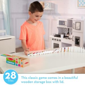 A boy is playing with Melissa & Doug Dominoes Tabletop Game 28 Colorful Tiles in a kitchen.