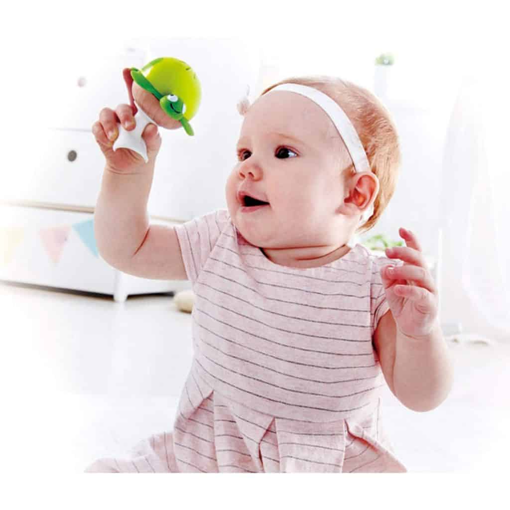 A baby is playing with the Hape Put-Stay Sea Animal Suction Rattle Set Three Toys.