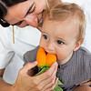 A woman feeding a baby the Oli & Carol Cathy the Carrot Mini Doudou Teether Natural Rubber.