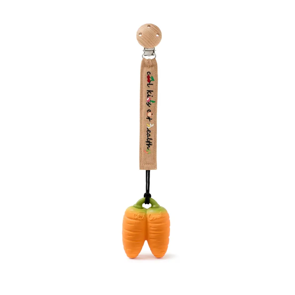 A wooden spoon with Oli & Carol Cathy the Carrot Mini Doudou Teether Natural Rubber on it.