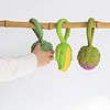A child is holding an Oli & Carol Corn Rattle Toy Teether Baby Natural Rubber on a bamboo branch.