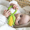 A baby is playing with an Oli & Carol Corn Rattle Toy Teether Baby Natural Rubber in a basket.