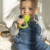 A baby is sitting in a basket with an Oli & Carol Corn Rattle Toy Teether Baby Natural Rubber.