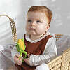 A baby is sitting in a basket holding an Oli & Carol Corn Rattle Toy Teether Baby Natural Rubber.