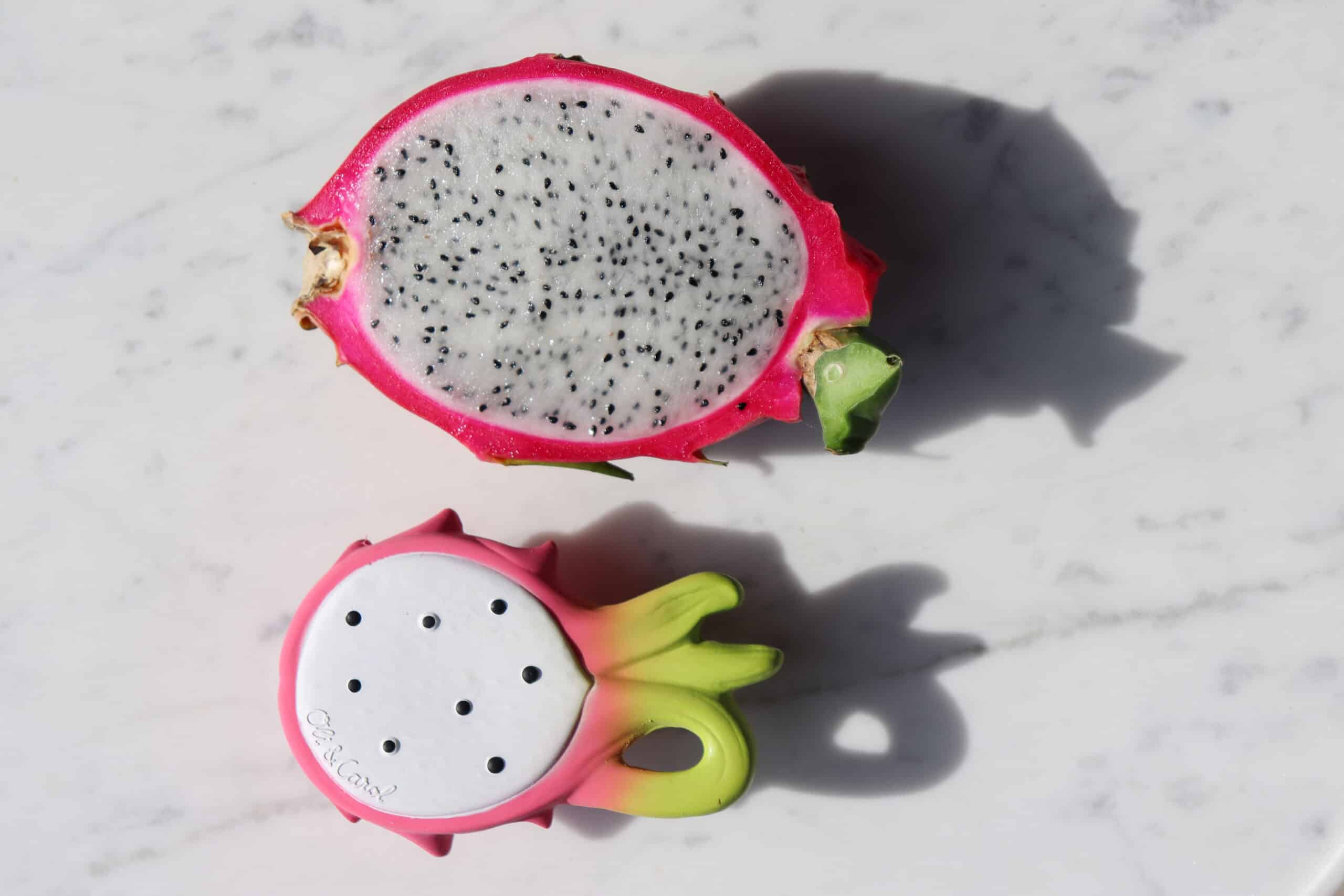Oli & Carol Fucsia de Dragonfruit Baby Teether Natural Rubber (5) An Oli & Carol Fucsia de Dragonfruit Baby Teether Natural Rubber is sitting on top of a marble table.