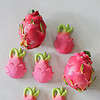 A group of Oli & Carol Fucsia de Dragonfruit Baby Teether Natural Rubber decorations on a white surface.