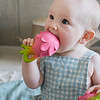 A baby is chewing on an Oli & Carol Fucsia de Dragonfruit Baby Teether Natural Rubber.