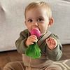 A baby is sitting on the floor with an Oli & Carol Ramona the Radish Baby Teether Natural Rubber in his mouth.