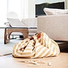 A yellow and white striped bean bag on the floor of a living room.