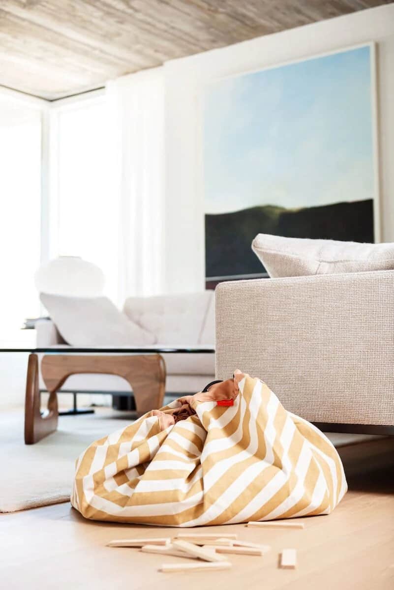 A yellow and white striped bean bag on the floor of a living room.