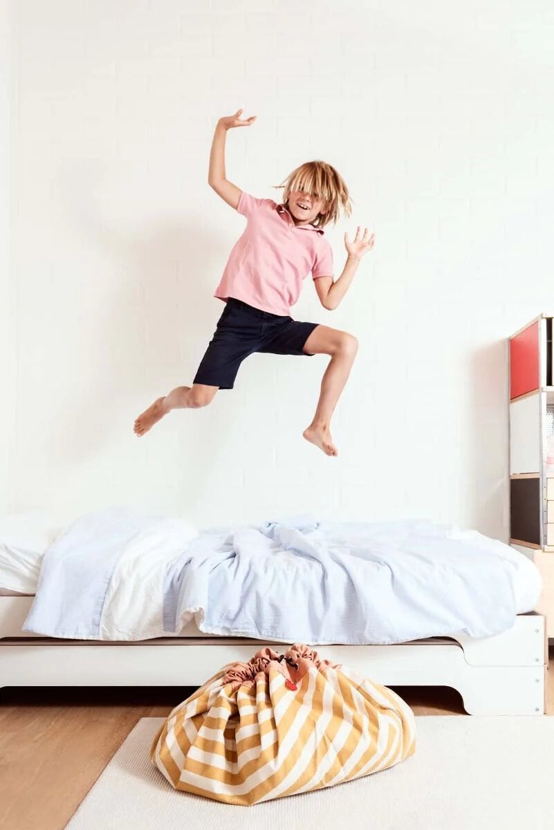 A young boy jumping on top of a bed.