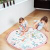 Two children playing with a pink play mat in a living room.