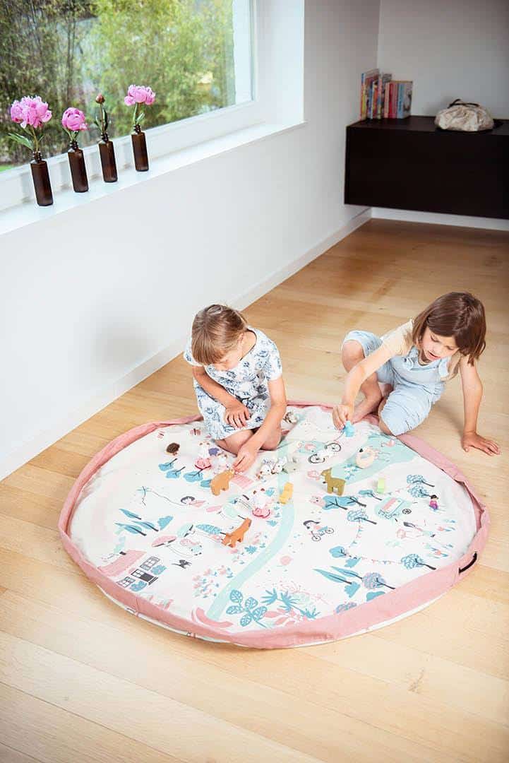 Two children playing with a pink play mat in a living room.