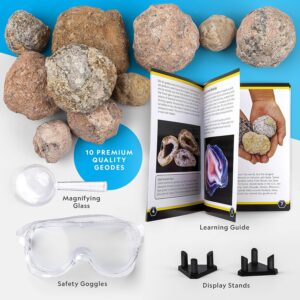 A National Geographic Break Open 10 Premium Geodes kit containing a learning guide, a magnifying glass, safety goggles, and two display stands. The geodes are shown alongside the educational materials on a white and blue background.