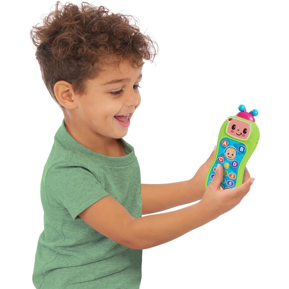 cocomelon-presslearnremote-37 A smiling young boy in a green shirt holds the CoComelon Press and Learn Remote Toddler Learning Toy, featuring colorful buttons and a cheerful cartoon face.
