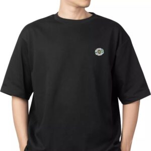 Person wearing a plain black T-shirt with a small circular Digimon Adventure Digivice Enamel Pin Hard Taichi Tribute Custom Fan Fanbase patch on the left chest.