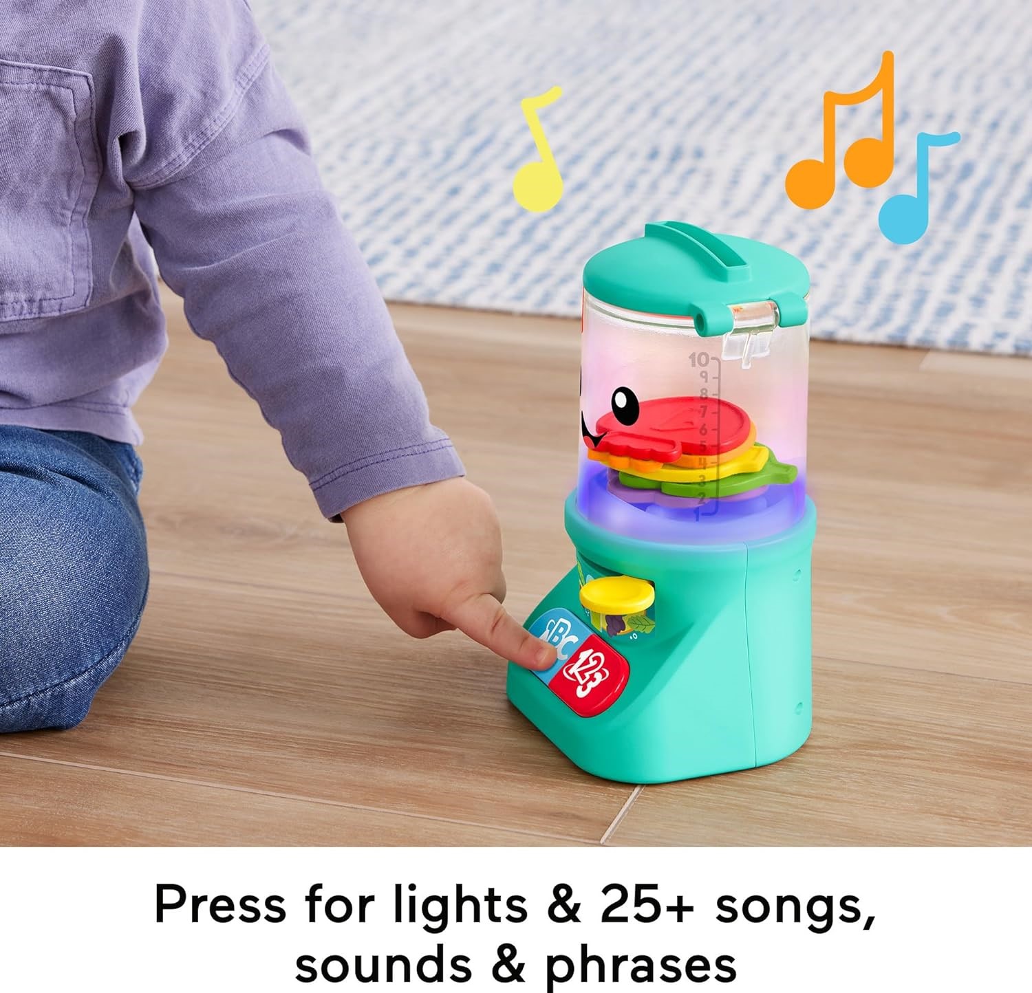 fisher-price-laugh-learn-counting-colors-smoothie-makers (5) A child presses a button on the Fisher-Price Laugh & Learn Baby & Toddler Toy Counting & Colors to activate lights and sounds. The toy features colorful music notes and a red fish inside. Text at the bottom reads, "Press for lights & 25+ songs, sounds & phrases.