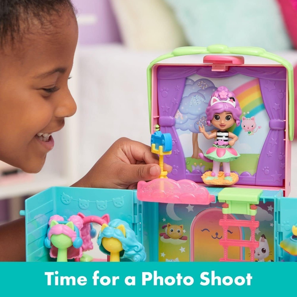 gabbydollhouse-dressupcloset-61 A child plays with the Gabby’s Dollhouse Dress-Up Closet Portable Playset, holding a blue accessory near the Gabby doll on stage. The text at the bottom reads, “Time for a Photo Shoot.”.