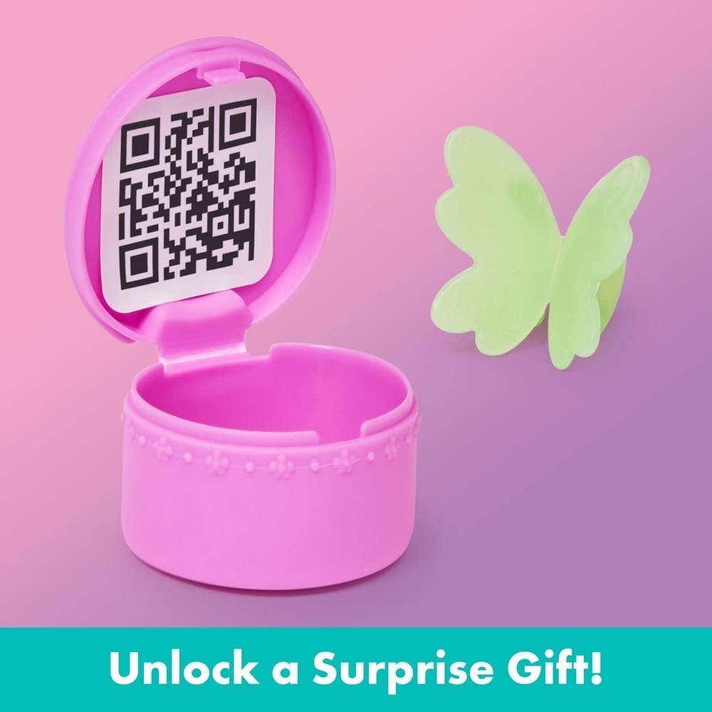 gabbydollhouse-dressupcloset-64 A pink plastic ring box with a QR code inside, a light green butterfly accessory, and the text “Unlock a Surprise Gift!” on a teal banner from the Gabby’s Dollhouse Dress-Up Closet Portable Playset Gabby Doll Surprise Toys Photo Shoot Netflix.