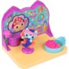 gabbydollhouse-mercatsparoom-80 Gabby’s Dollhouse MerCat’s Spa Room Playset features a MerCat figure seated in a chair, a mirrored backdrop, a pink accessory, and a blue bowl filled with pink beads on a yellow and purple base.