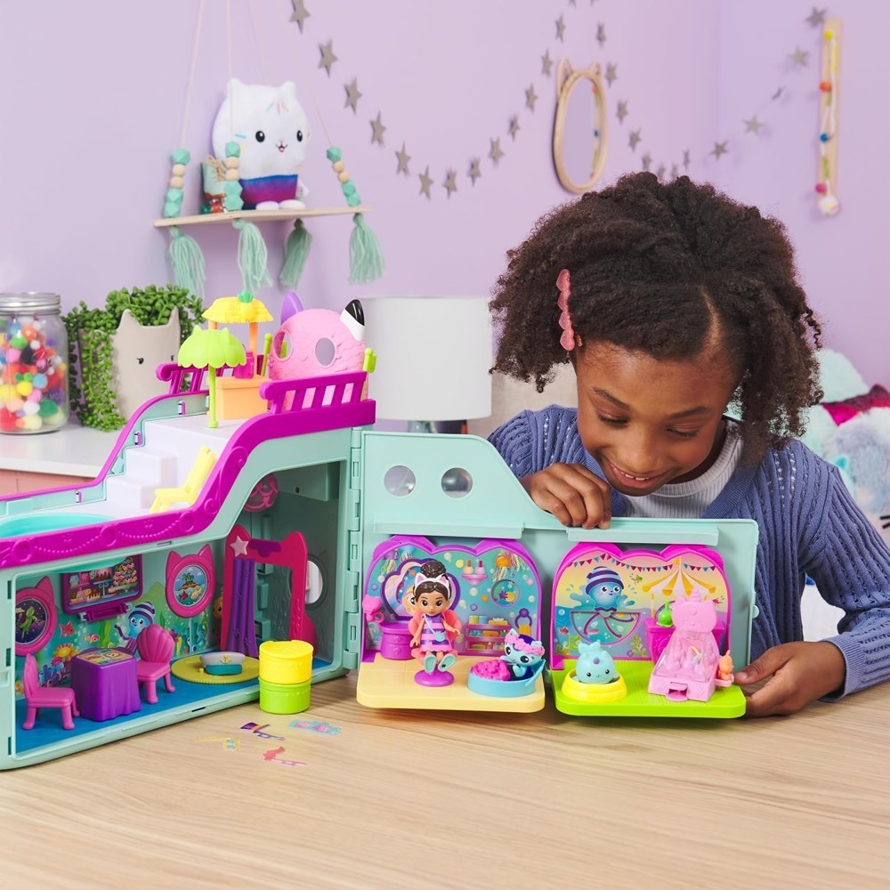 gabbydollhouse-mercatsparoom-85 A young girl plays with the Gabby’s Dollhouse MerCat’s Spa Room Playset, which features a MerCat figure, surprise dollhouse furniture, and fun accessories on a table in a decorated room.
