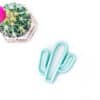 A cactus plant and a cactus cookie cutter on a white table.