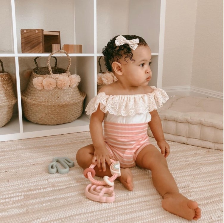 A baby girl in a pink and white striped romper.