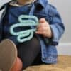 A baby is sitting on a rug with a green cactus toy.