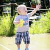 A baby is playing with a water hose.