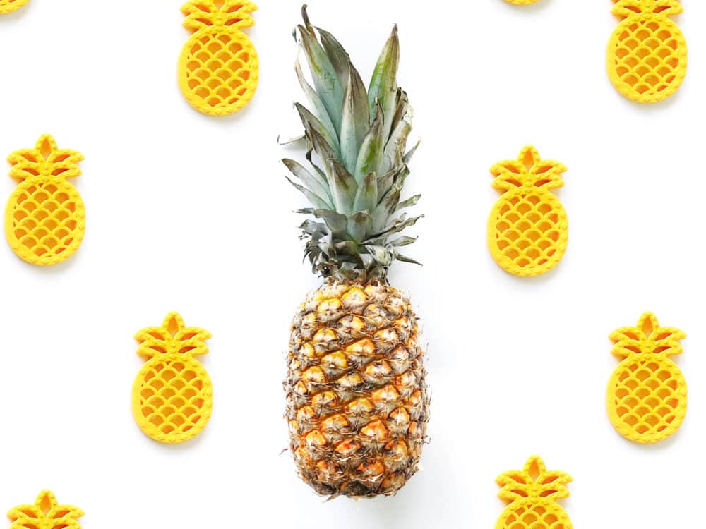 A pineapple is surrounded by a group of yellow pineapples.