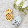 A pineapple and cactus on a rug next to a plant.