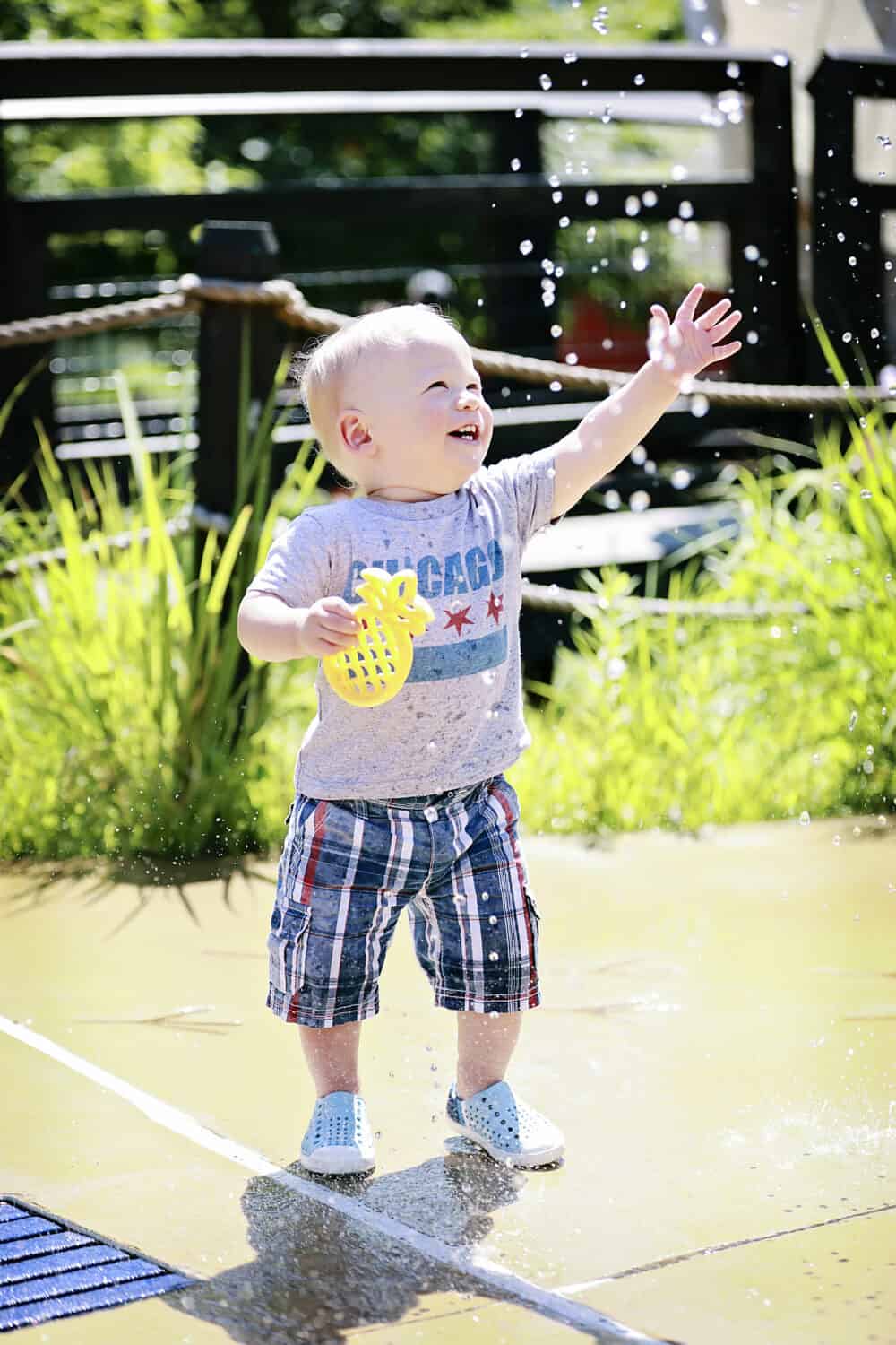 A baby is playing with a water hose.