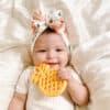 A baby wearing a headband holding a pineapple toy.