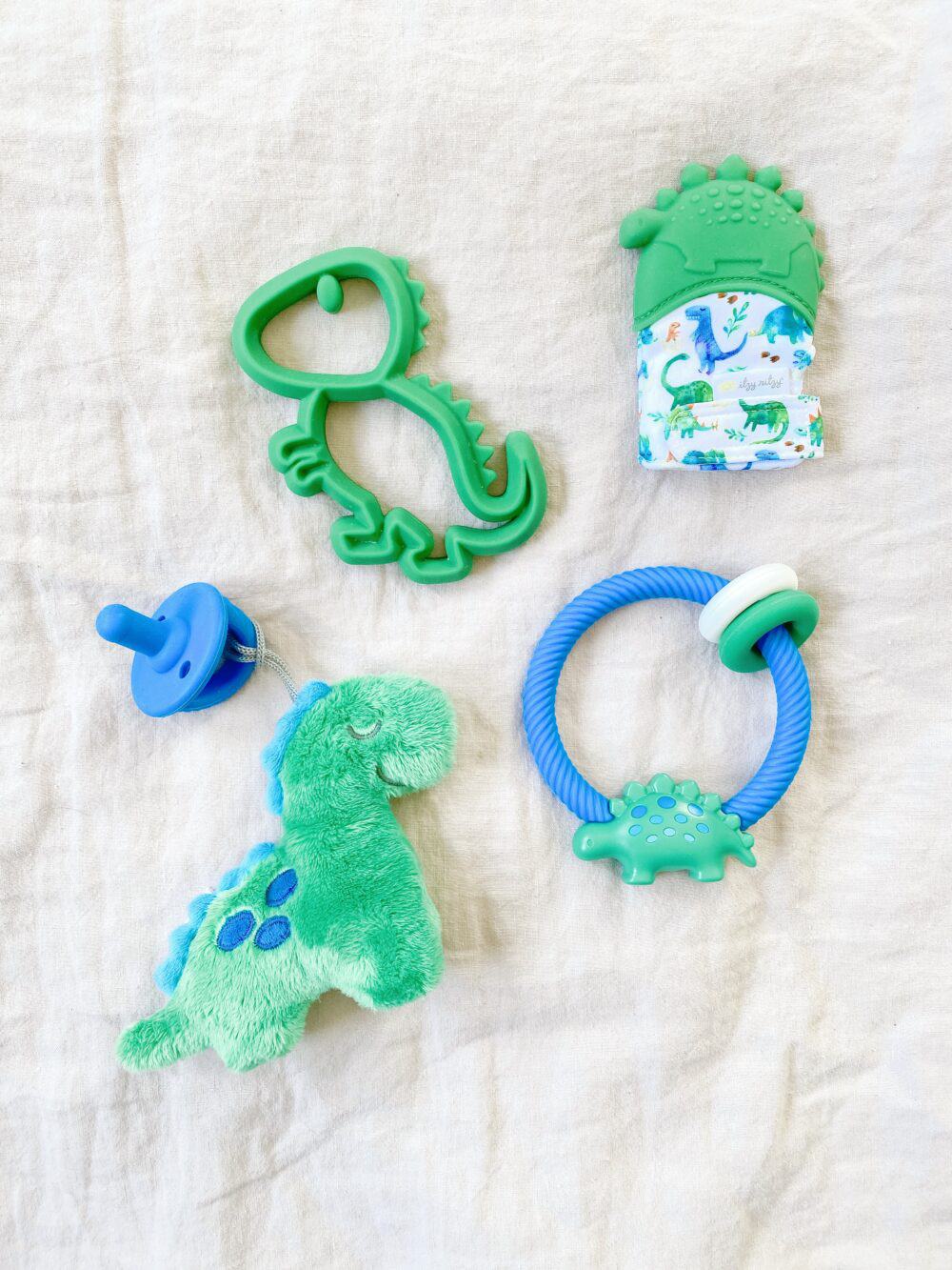 A set of blue and green dinosaur toys on a bed.