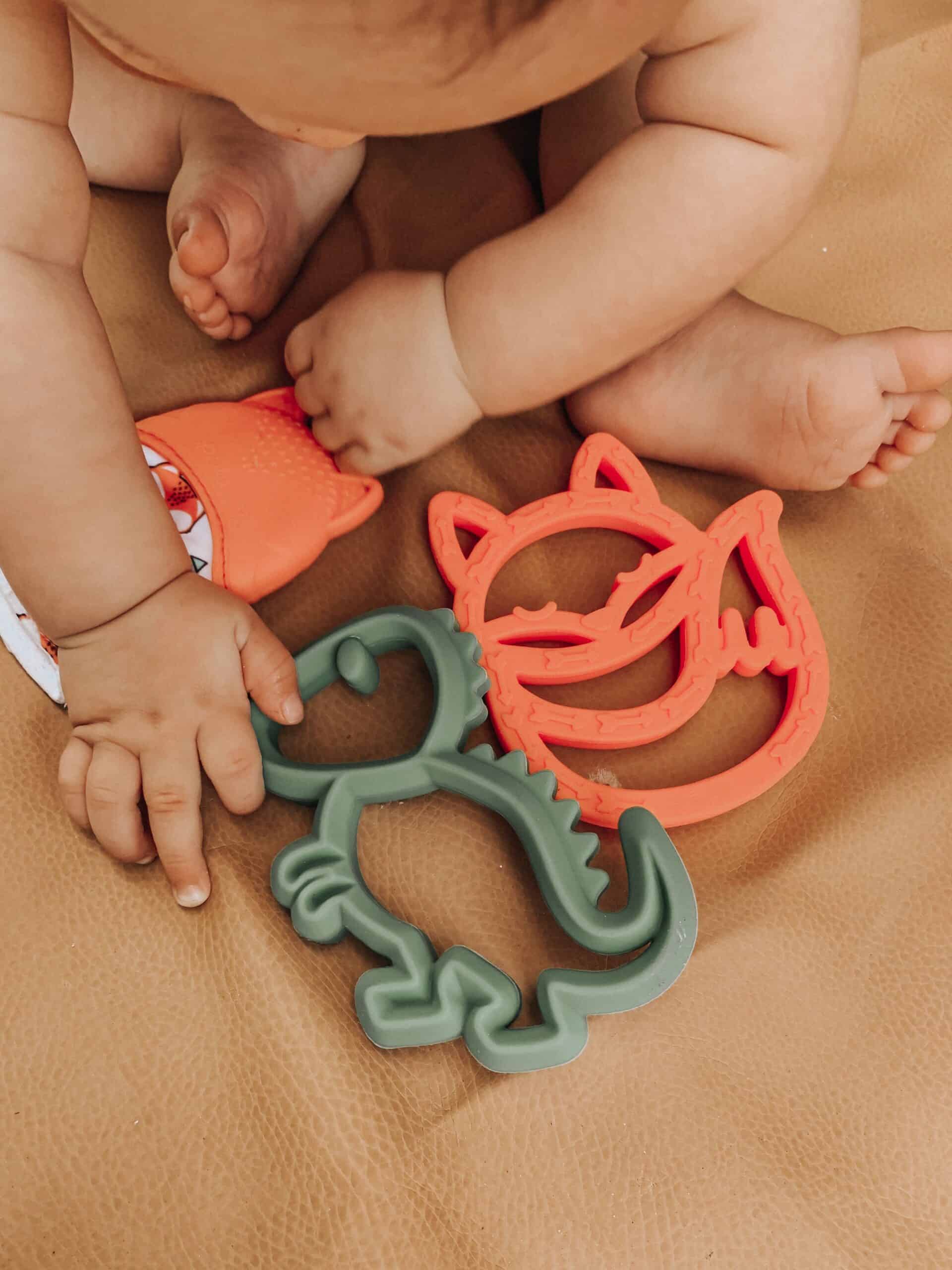 A baby is playing with a set of teethers.