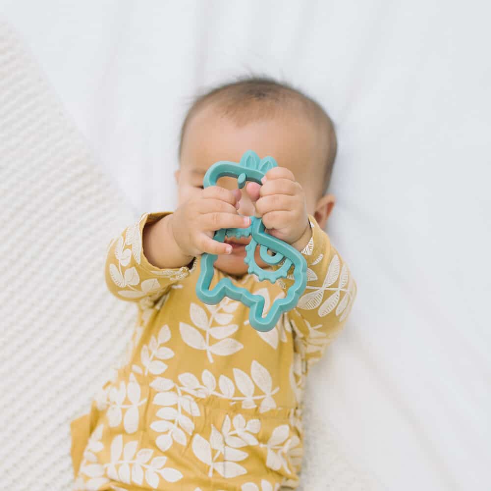 A baby is playing with a toy on a bed.