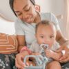 A woman holding a baby while holding a blue pacifier.