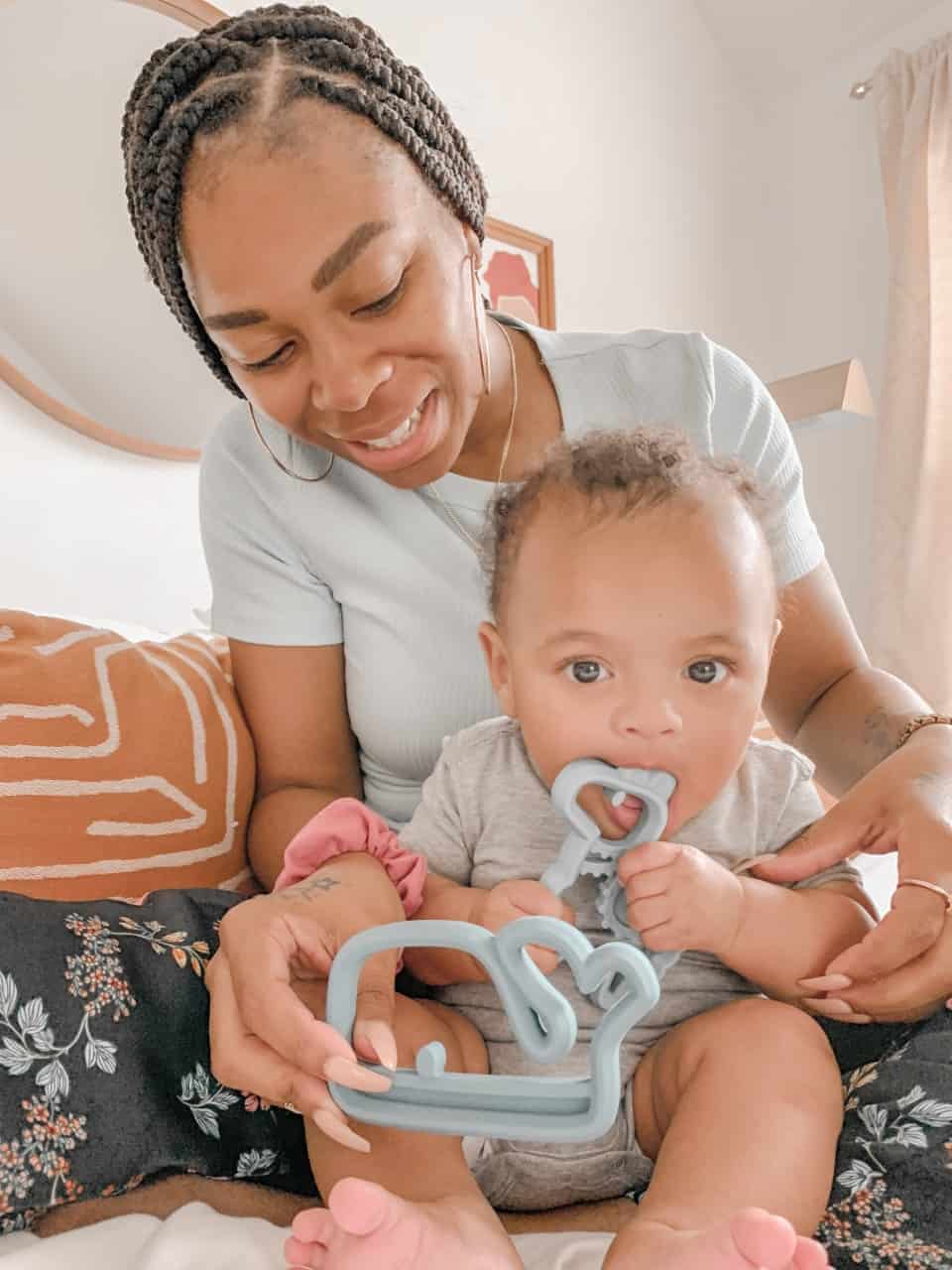 A woman holding a baby while holding a blue pacifier.