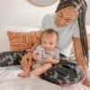 A woman is sitting on a bed with a baby on her lap.