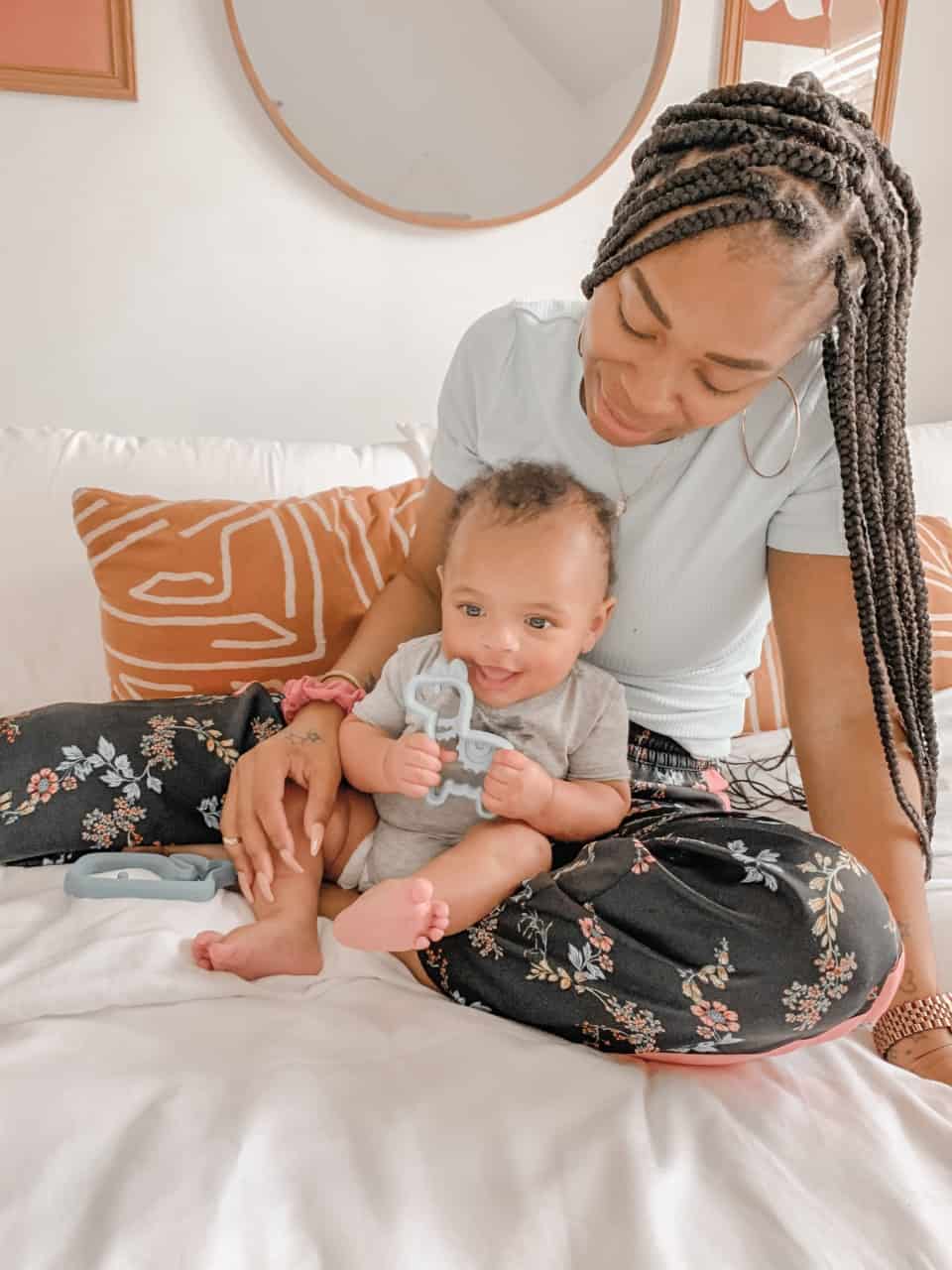 A woman is sitting on a bed with a baby on her lap.