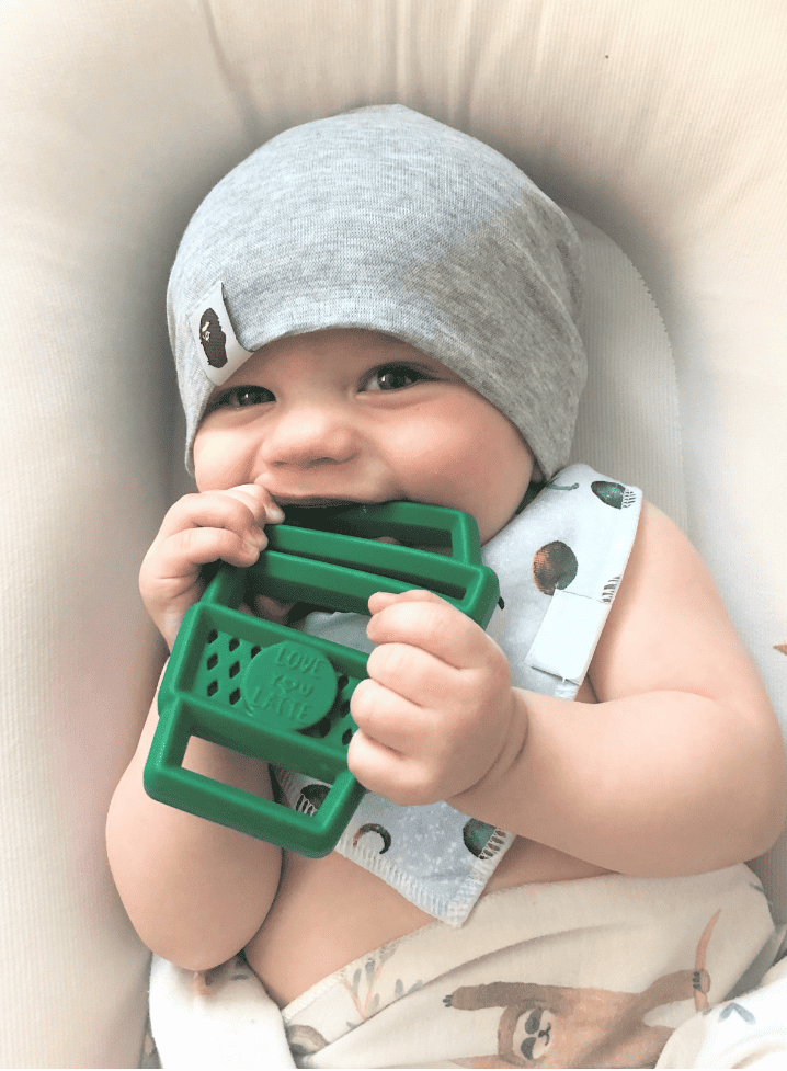 A baby is chewing on a Chew Crew Silicone Baby Teether.