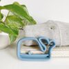 A blue whale shaped teether on a shelf next to a plant.