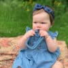 A baby is sitting on a blanket eating a toy.