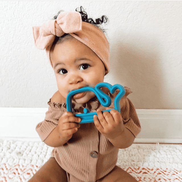 A baby is holding a blue whale toy.