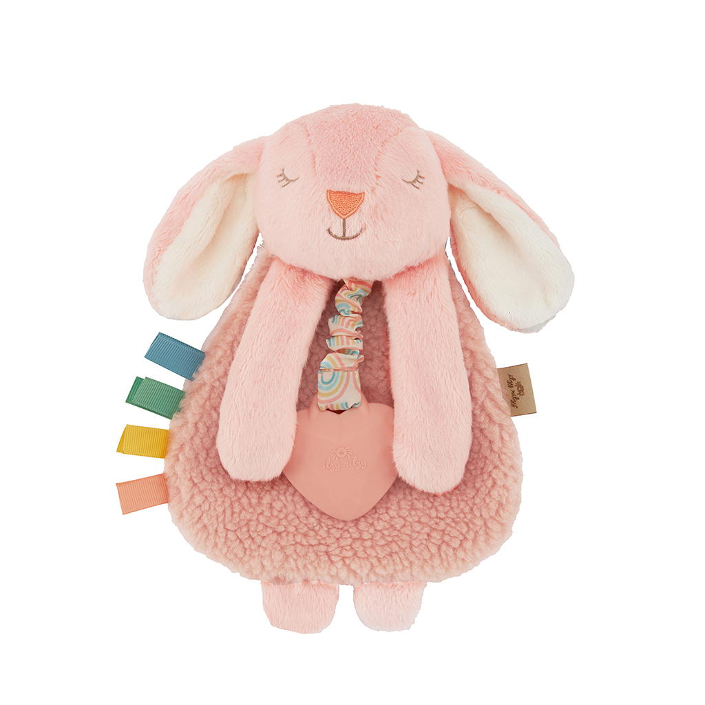 A soft, pink plush bunny toy with long ears and various colorful fabric tags attached to its side, holding a heart-shaped accessory.