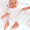 A baby laying on a bed with a book on it.